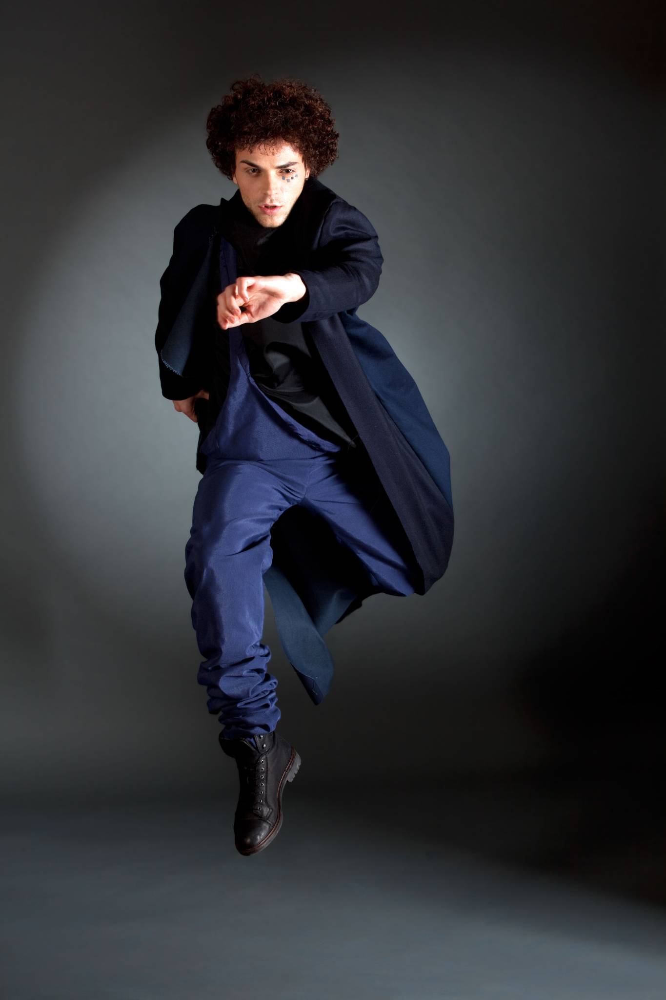 Male Model in blauen Umhang, Hose, springend