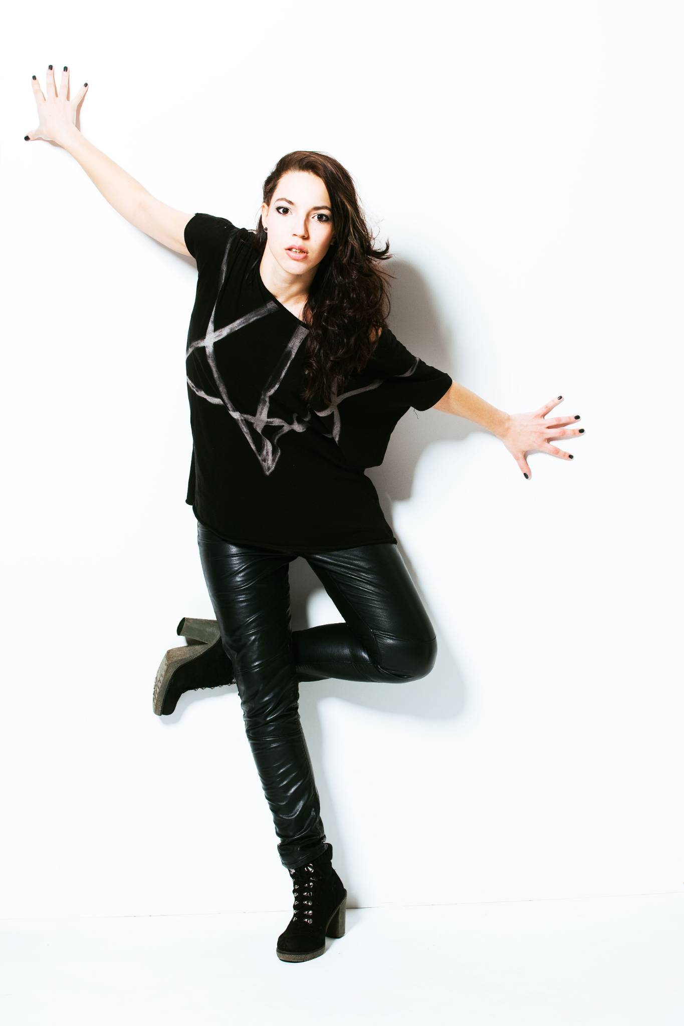 junge Frau posiert in T-Shirt und Jeans an Wand